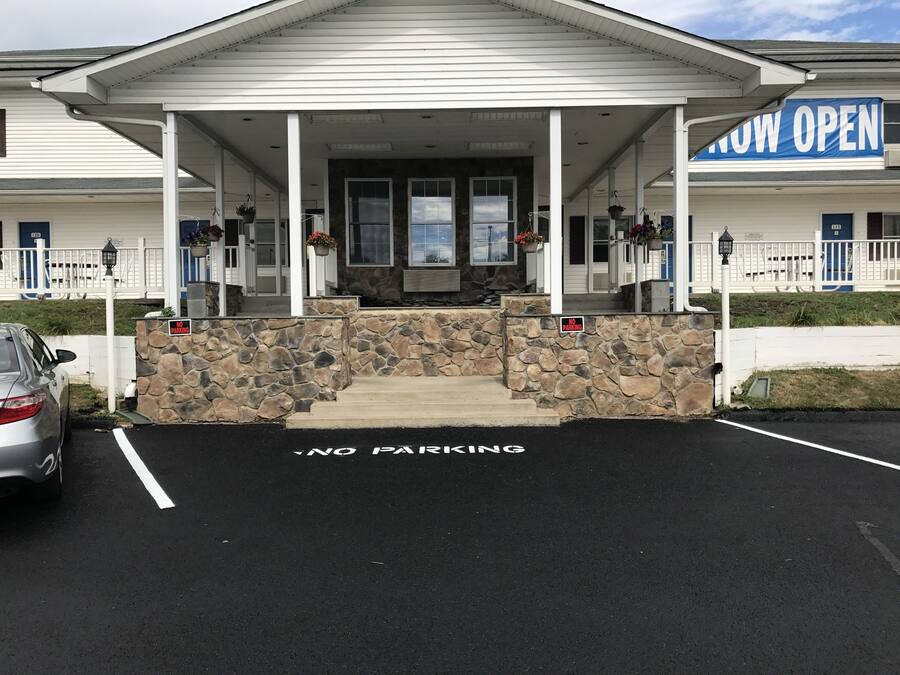 Un bâtiment doté d’une façade en pierre, d’une entrée abritée et d’un panneau indiquant « Stationnement interdit » au niveau du sol.