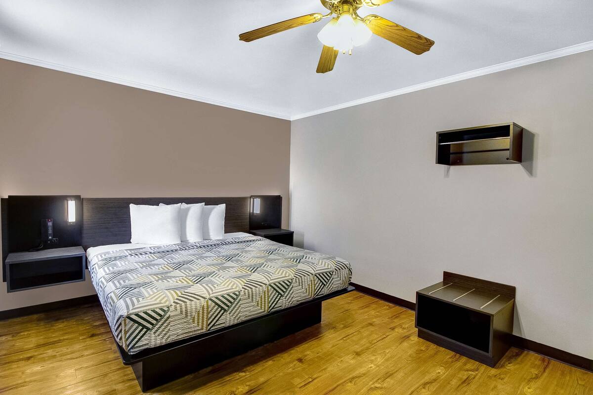 A modern bedroom with a bed, wooden floor, a ceiling fan, and built-in nightstands.