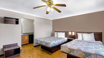 A hotel room with two beds, a ceiling fan, a mirror, and a small cabinet.