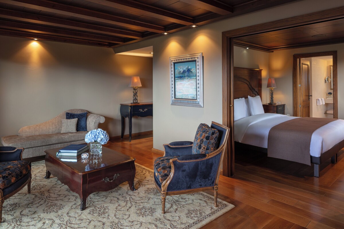 A well-lit room with a bed, a sofa, a chair, and a coffee table.