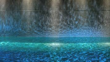 A pool with clear water and a textured wall in the background.