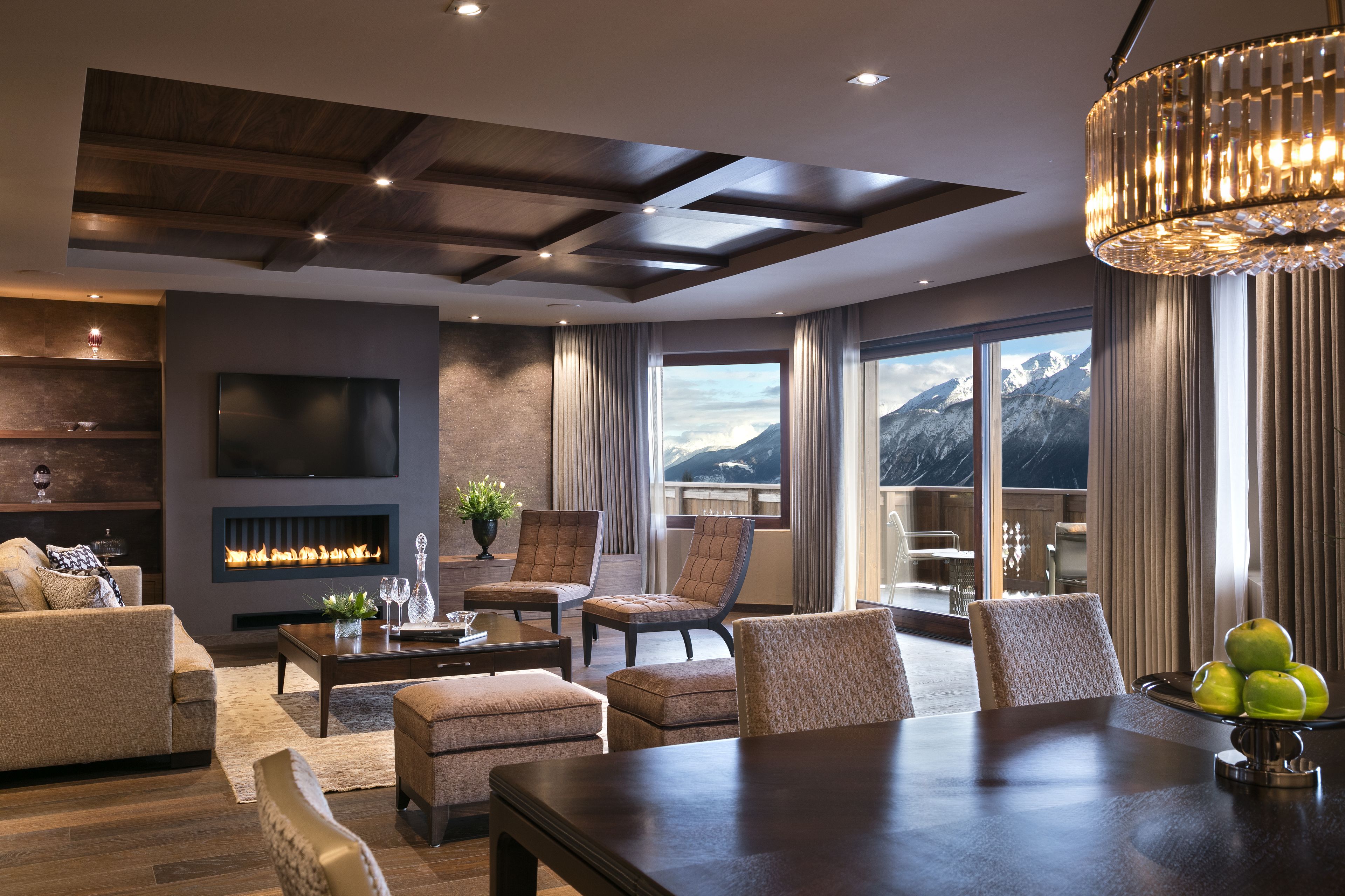 A modern living room with a fireplace, comfortable seating, a dining table, and a large window offering a mountain view.
