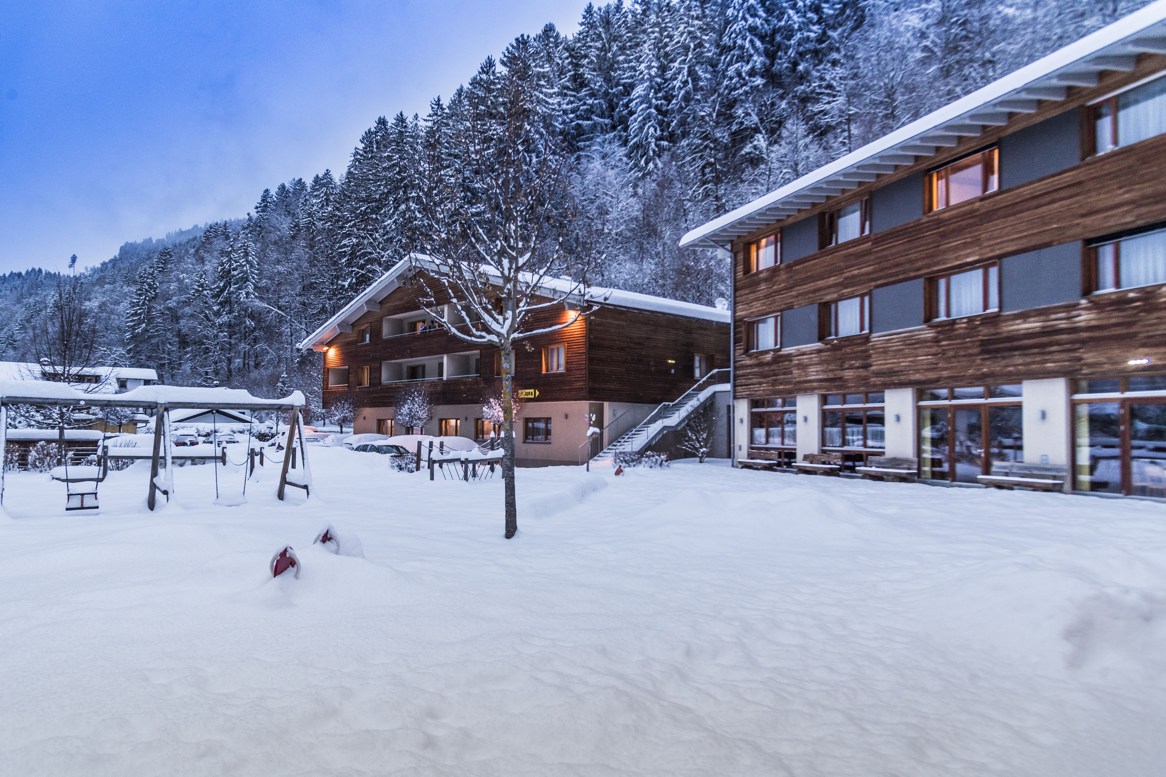 A snow-covered outdoor area with a wooden building and a modern glass structure.