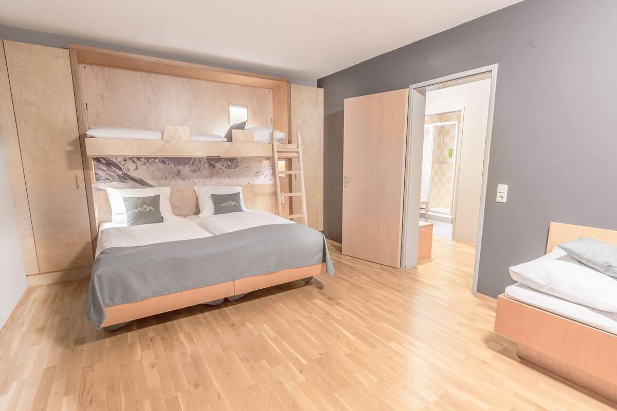 A modern bedroom with a bed, built-in wardrobe, and a bathroom visible through an open door.