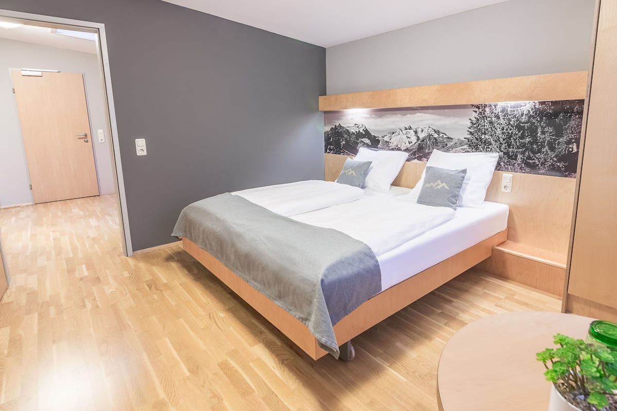 A modern bedroom with a wooden bed, grey walls, and a wooden headboard.