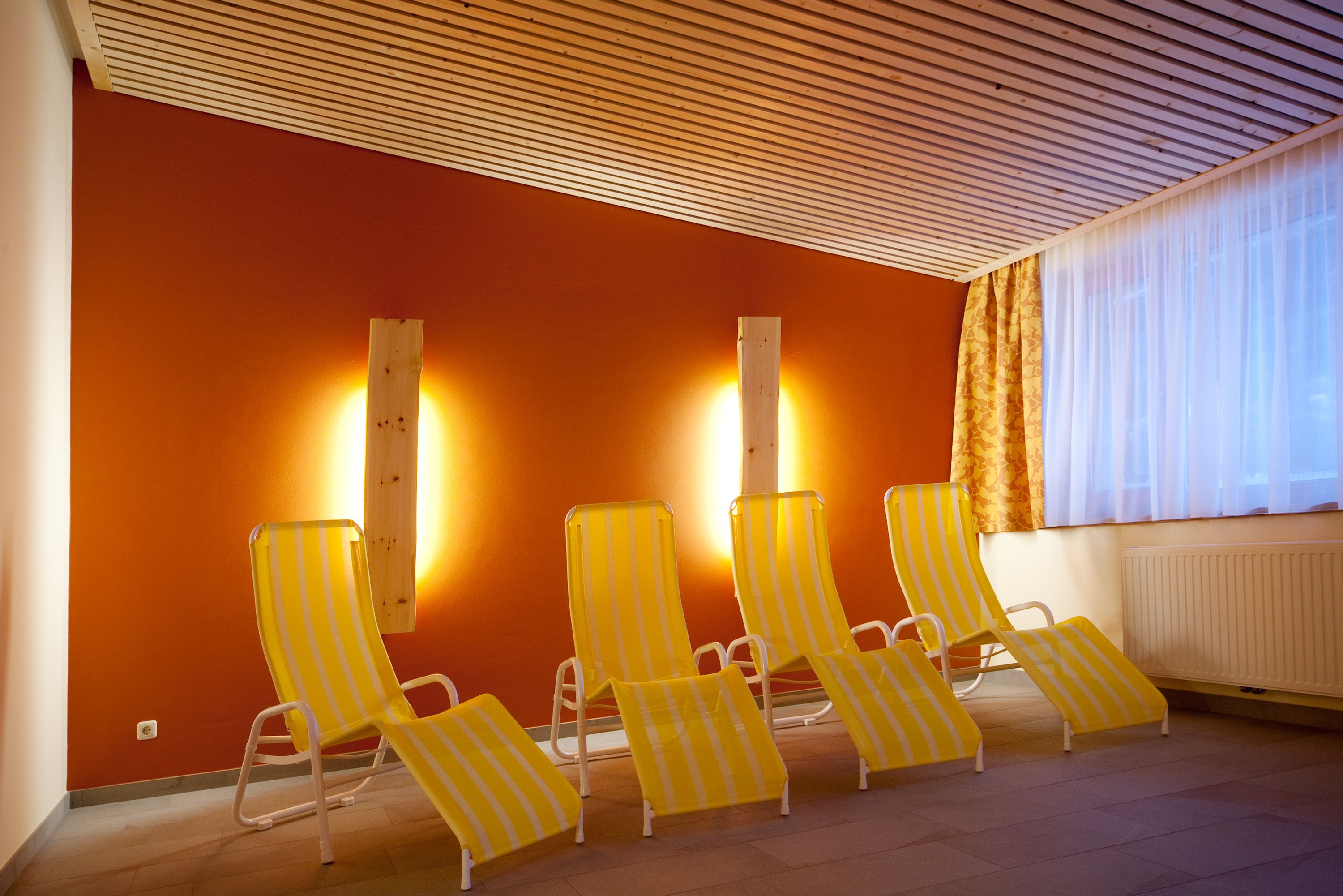 Una stanza con quattro poltrone a righe, un soffitto in legno e una finestra con tende.