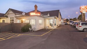 A motel with a neon sign, a parking lot, and several parked cars. - 540 on Great South Motel (Auckland)