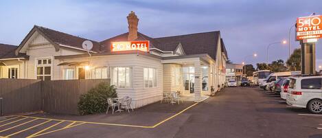 Un motel con insegna al neon, un parcheggio e diverse auto parcheggiate.