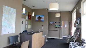 A reception area with a desk, computer, and seating area. There are wall decorations and a map on the wall. - 540 on Great South Motel (Auckland)
