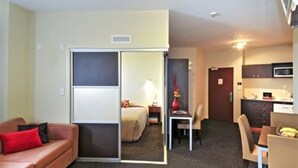 A hotel room with a sliding door separating the living area and bedroom. There is a sofa, a dining table with chairs, and a kitchenette with a microwave. - 540 on Great South Motel (Auckland)