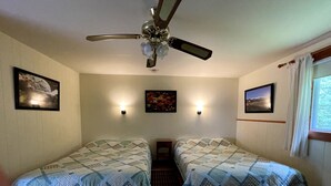 A room with two beds, a ceiling fan, wall-mounted lights, and framed pictures. - The Riverside Inn (Stowe)