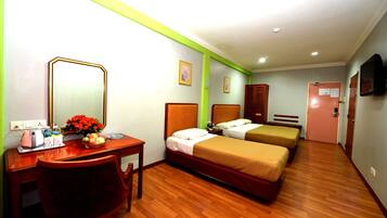 A hotel room with two beds, a desk with a chair, a mirror, and a small table with a vase of flowers.