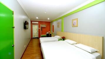 A hotel room with two beds, a desk, and a green door.