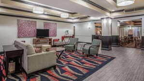 A hotel lobby with a sofa, chairs, a TV, and a dining area. - La Quinta Inn & Suites by Wyndham Conway (Conway)