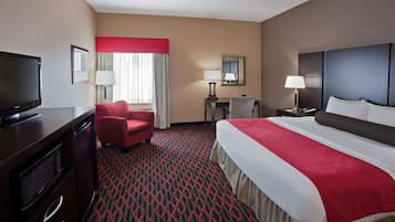 A hotel room with a large bed, a TV, a desk, and a chair.