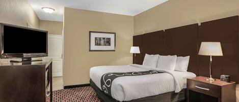 A hotel room with a bed, bedside tables, a TV, and a patterned carpet.