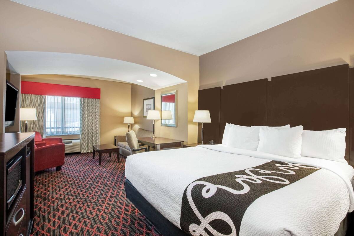 Una habitación de hotel con una cama grande, un escritorio, una silla y un televisor.