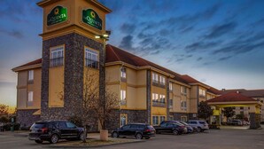 A hotel with a prominent tower, multiple parking spaces, and a clear sky. - La Quinta Inn & Suites by Wyndham Conway (Conway)