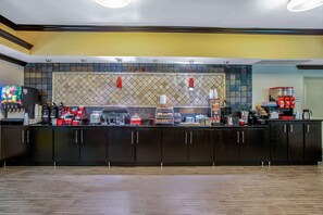 A modern kitchen area with a tiled backsplash, black cabinets, and various appliances. - La Quinta Inn & Suites by Wyndham Conway (Conway)
