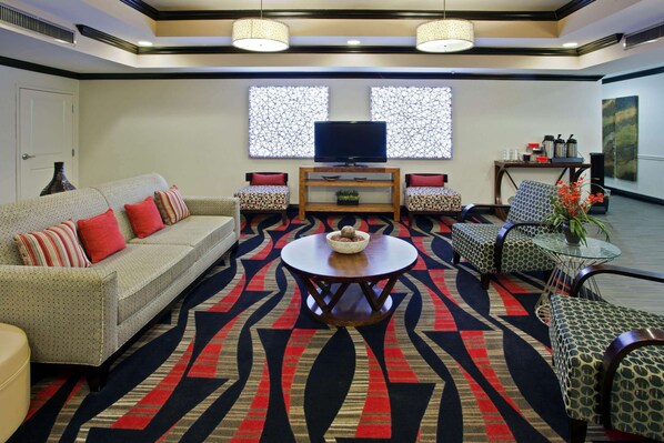 A modern living room with a sofa, armchairs, a coffee table, and a TV. - La Quinta Inn & Suites by Wyndham Conway (Conway)