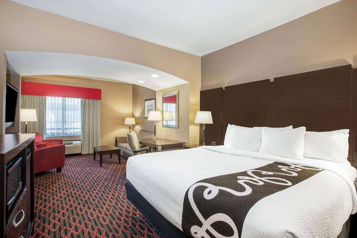 Una habitación de hotel con una cama grande, un escritorio, una silla y un televisor.