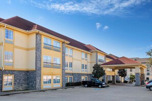 A multi-story hotel with a yellow facade, stone accents, and a red-tiled roof. - La Quinta Inn & Suites by Wyndham Conway (Conway)