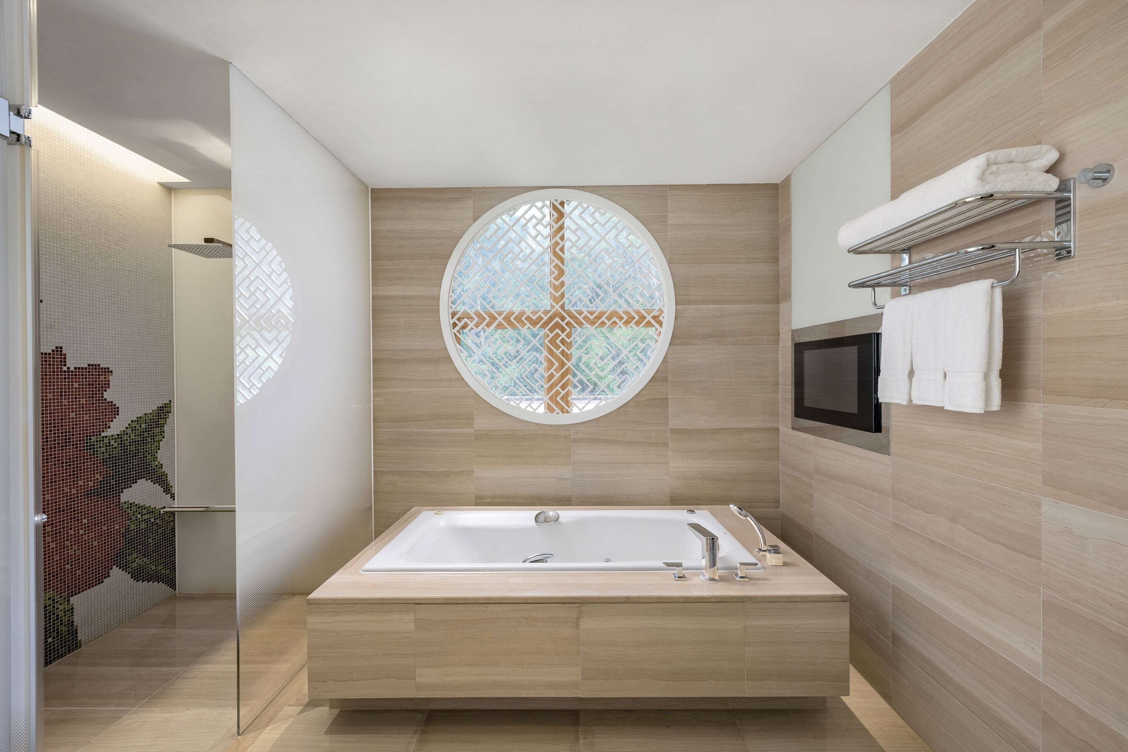 A modern bathroom with a freestanding bathtub, a glass partition, and a wall-mounted TV.