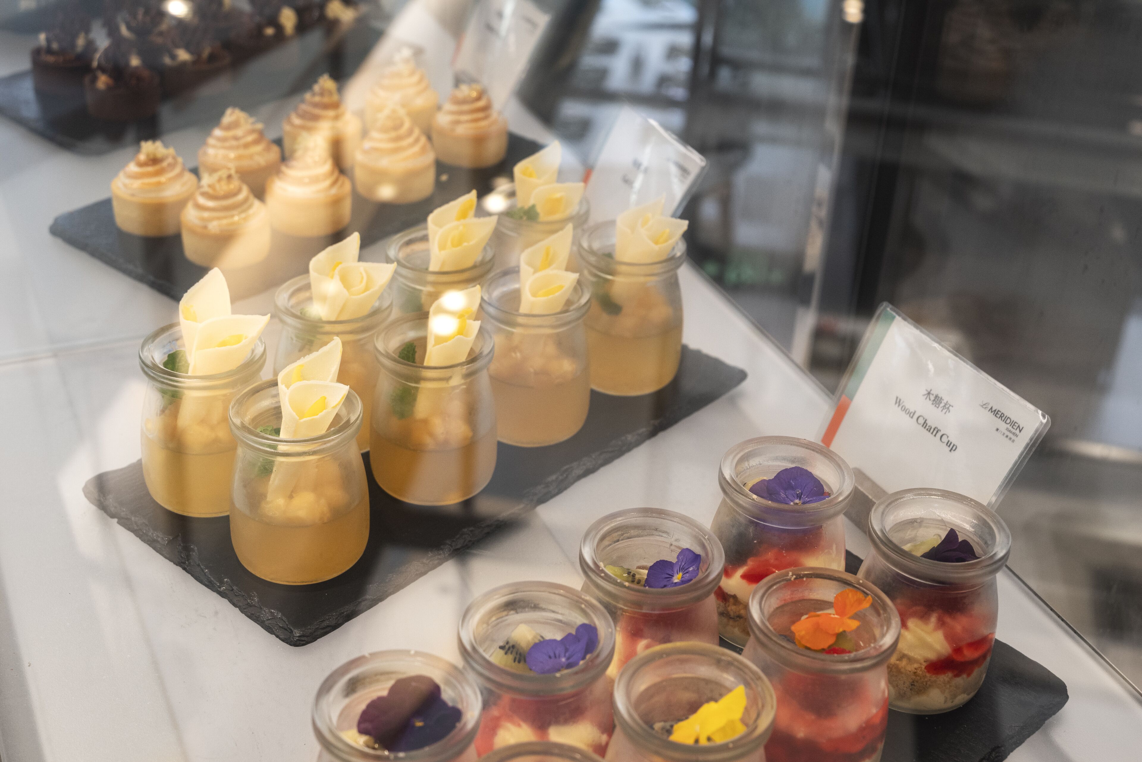 A display of desserts in glass jars with various toppings and decorations.