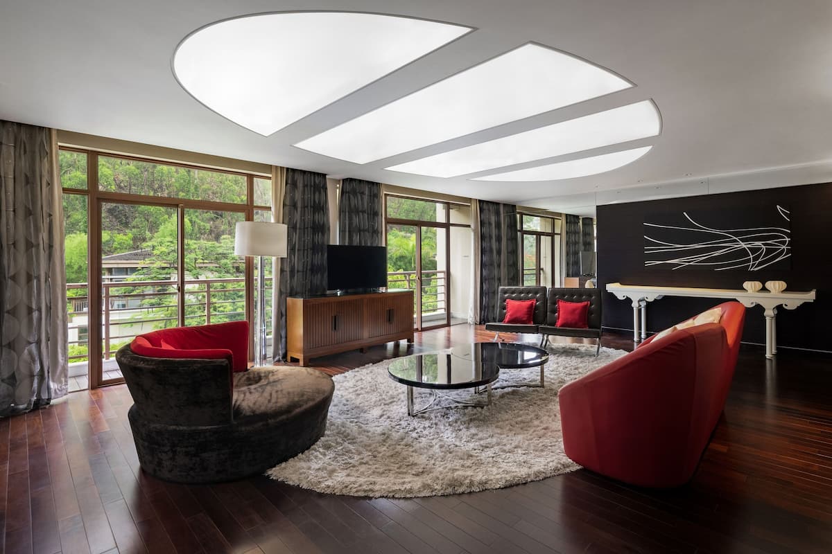 A modern living room with a large window, a round glass coffee table, and a red sofa.