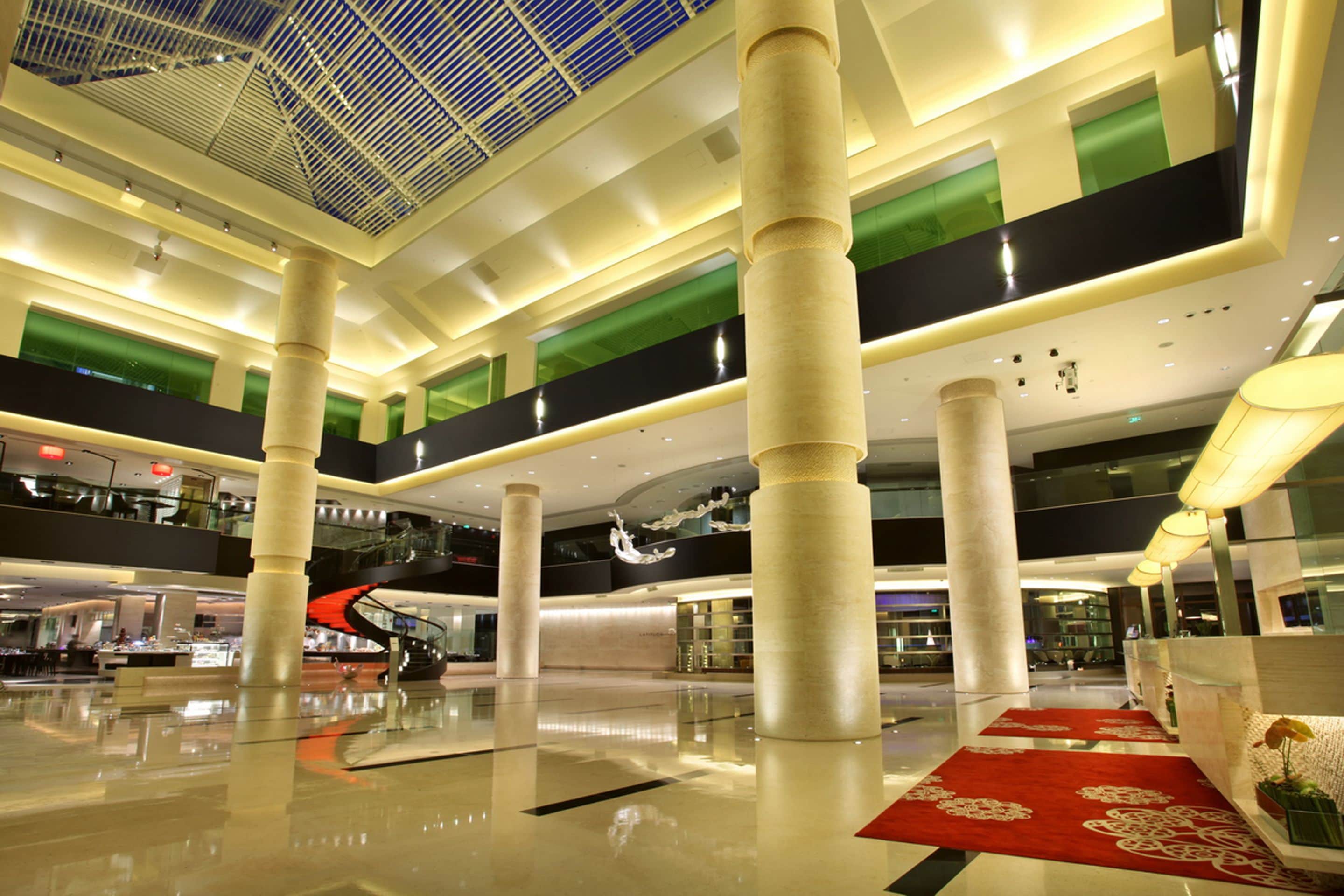 A spacious indoor area with high ceilings, large columns, and a central staircase.