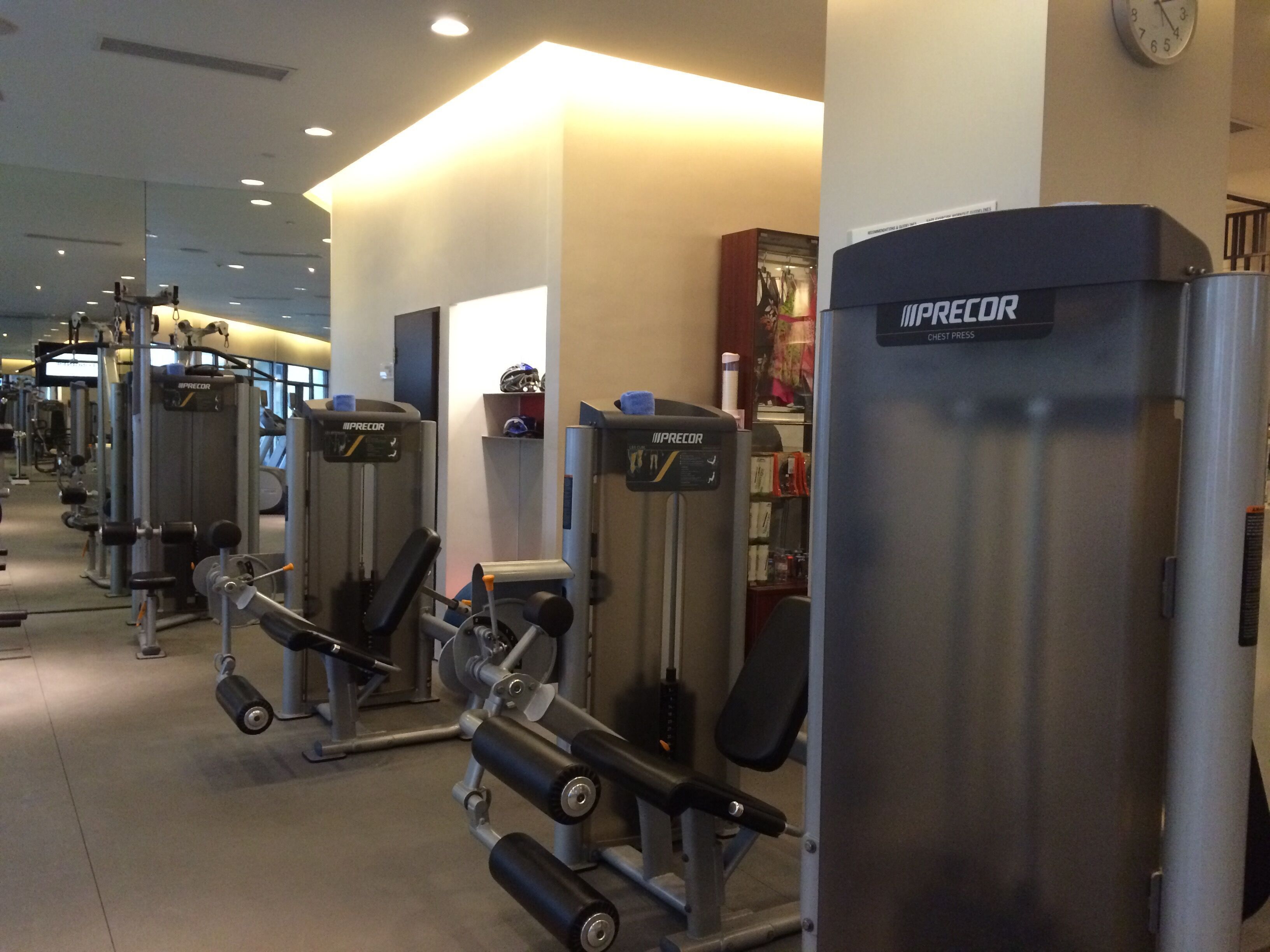 A gym with various exercise machines, including a chest press machine labeled "IMPRECOR CHEST PRESS".