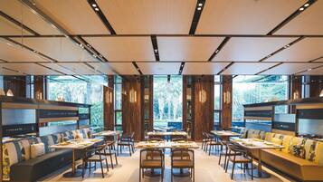 A modern restaurant with a central dining area, booths, and a view of the outdoors.