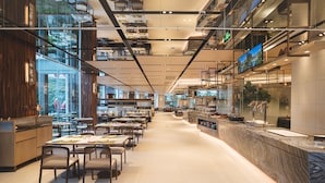 Un restaurante espacioso con techos altos, iluminación moderna y una larga barra con asientos.