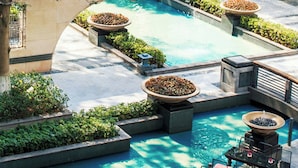 Zona de piscina con varias opciones de asientos y una fuente.