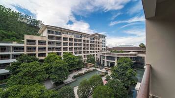 A multi-story hotel with a central courtyard, a swimming pool, and lush greenery.