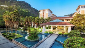 A resort with multiple swimming pools, palm trees, and a building with a red roof.
