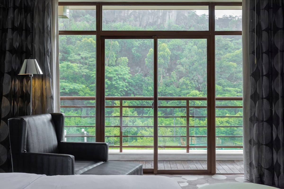 A room with a large window offering a view of a forested area.