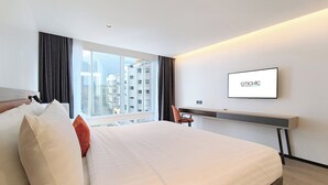 A modern hotel room with a large bed, a desk, and a TV.