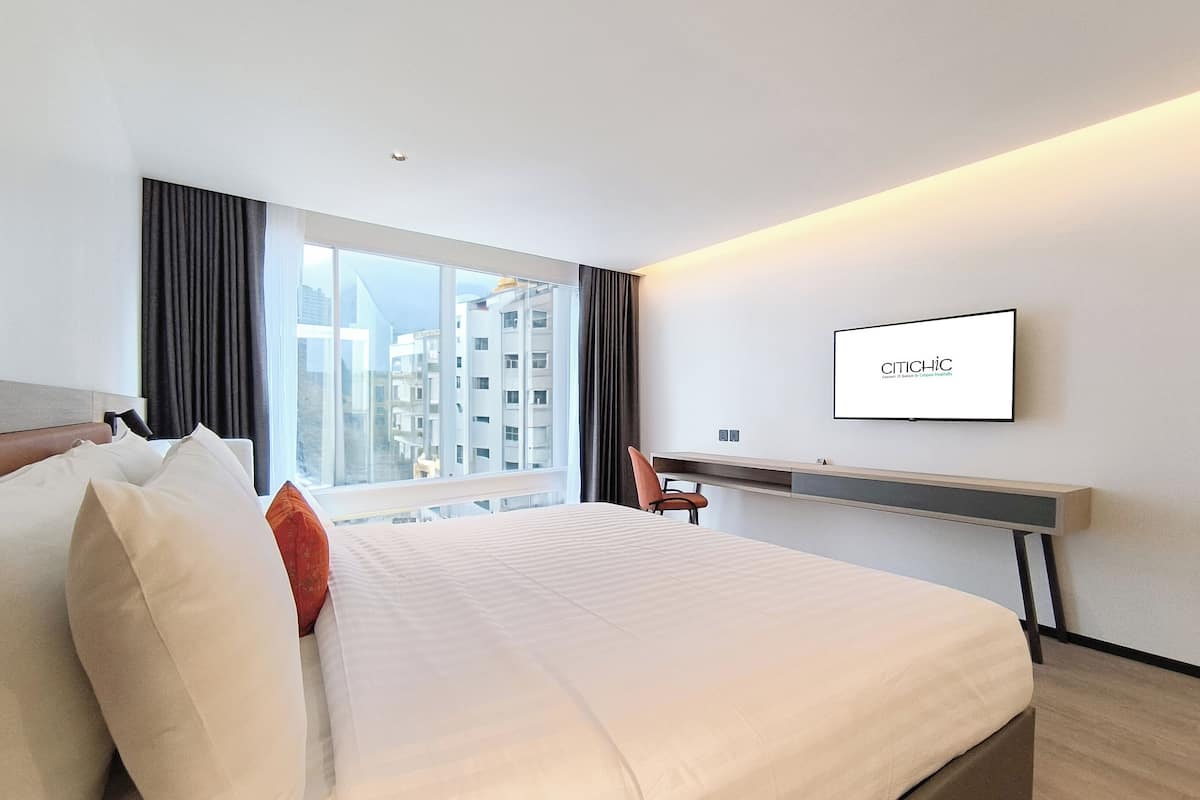 Ein modernes Hotelzimmer mit einem großen Bett, einem Schreibtisch und einem Fernseher.