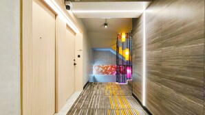 A hallway with wooden doors, a patterned carpet, and a wall with a textured finish.