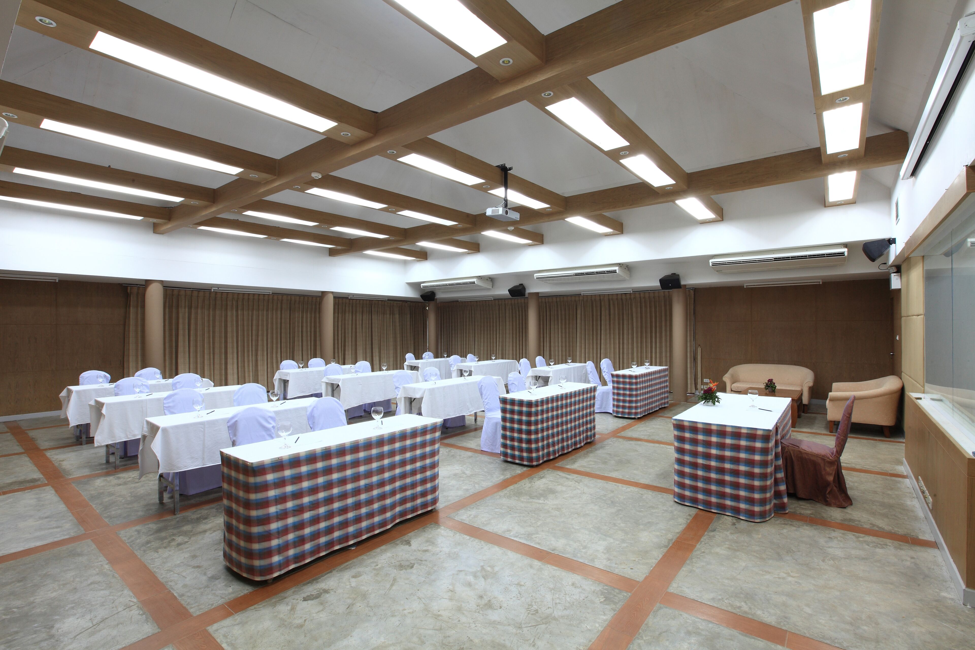 Una sala conferenze con diversi tavoli e sedie, un palco e una zona con posti a sedere.