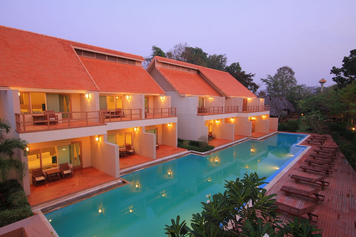Ein Resort mit Schwimmbad, mehreren Gästezimmern und einer überdachten Terrasse.