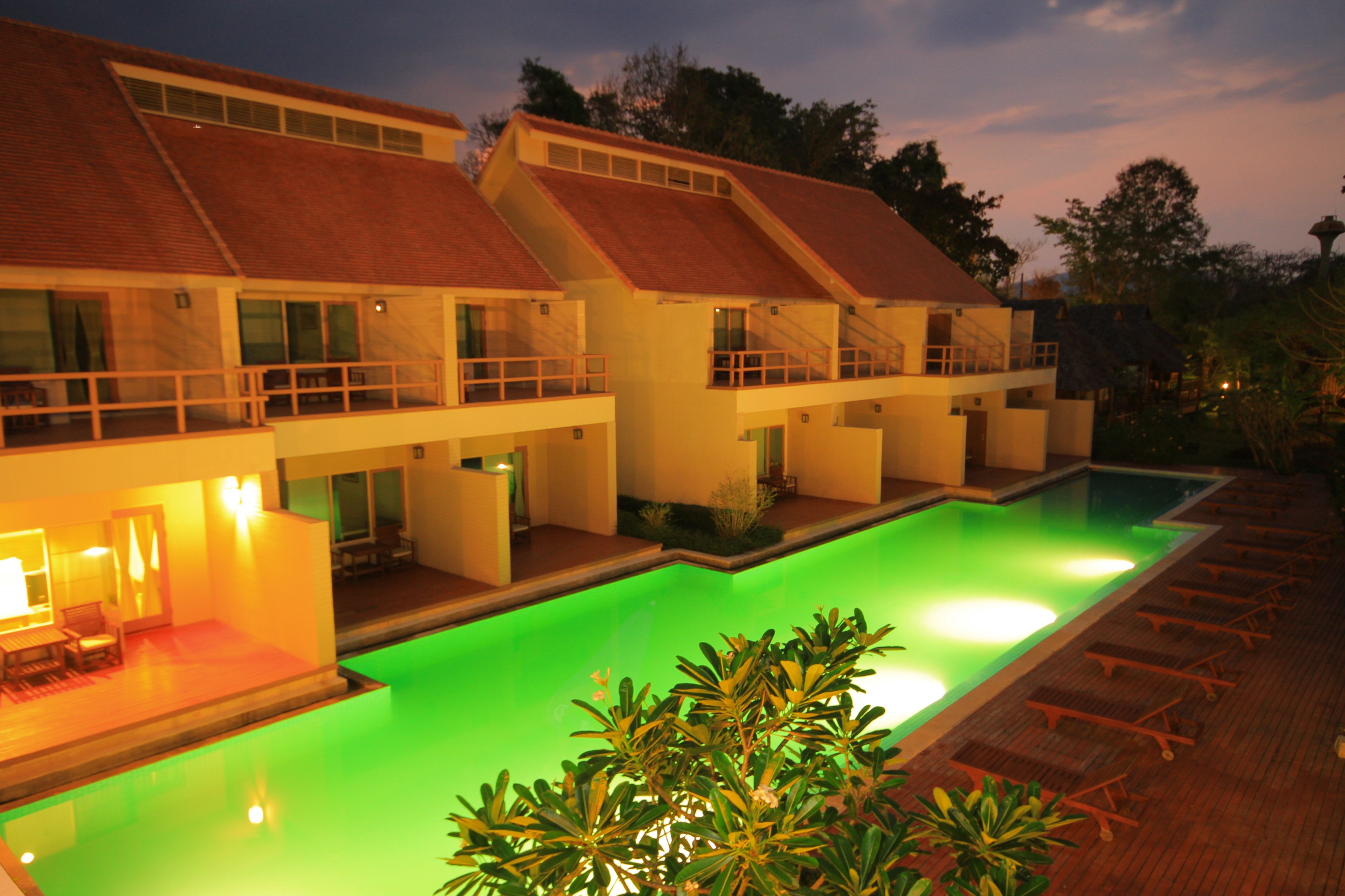 A hotel with a swimming pool, multiple balconies, and a well-lit outdoor area.
