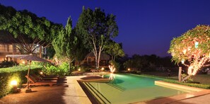 A nighttime swimming pool area with lounge chairs, a well-lit pathway, and surrounding greenery. - Belle Villa Resort Pai (Pai)