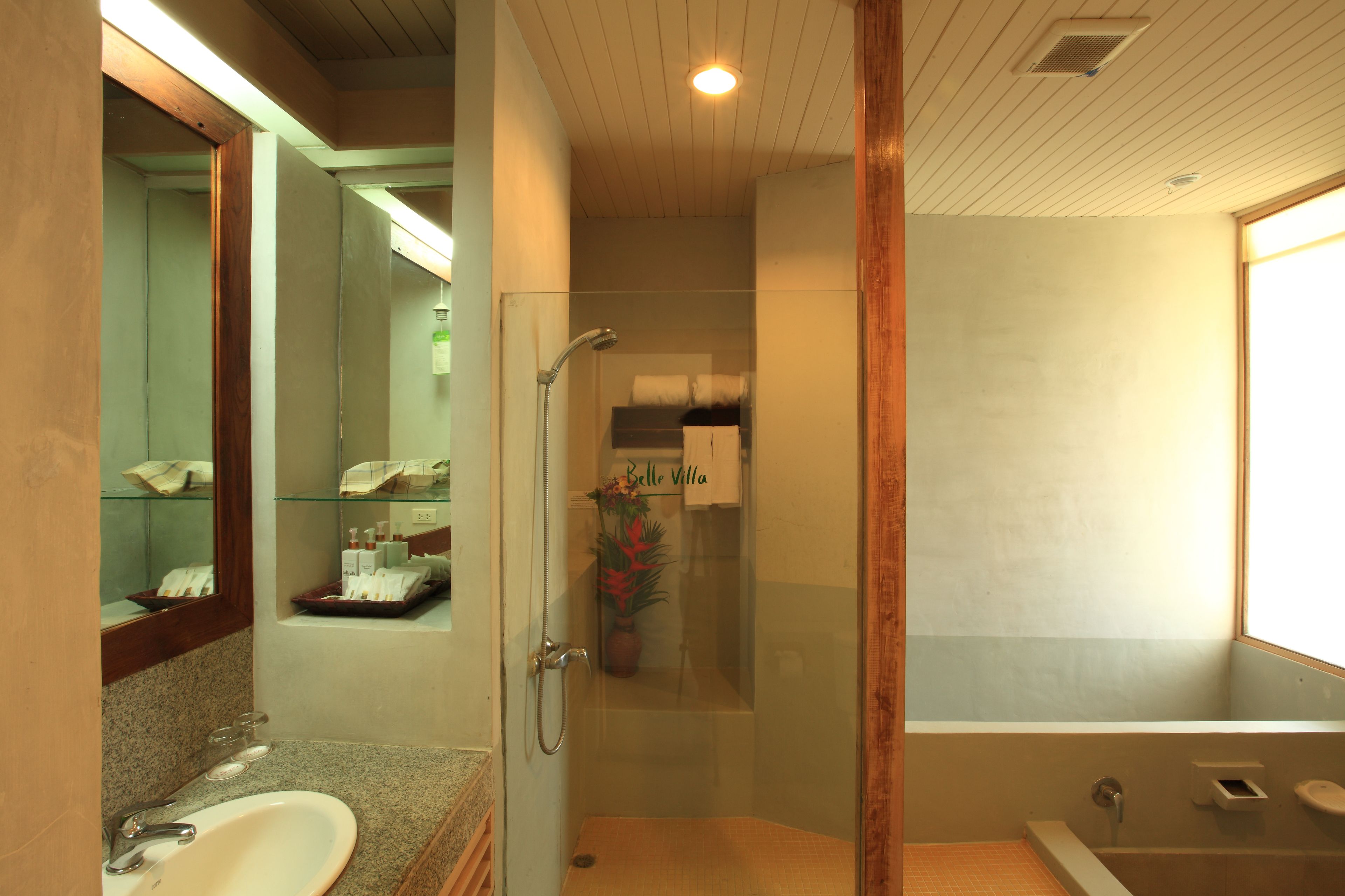 Un baño con ducha envuelta en vidrio, un espejo grande y una bañera.