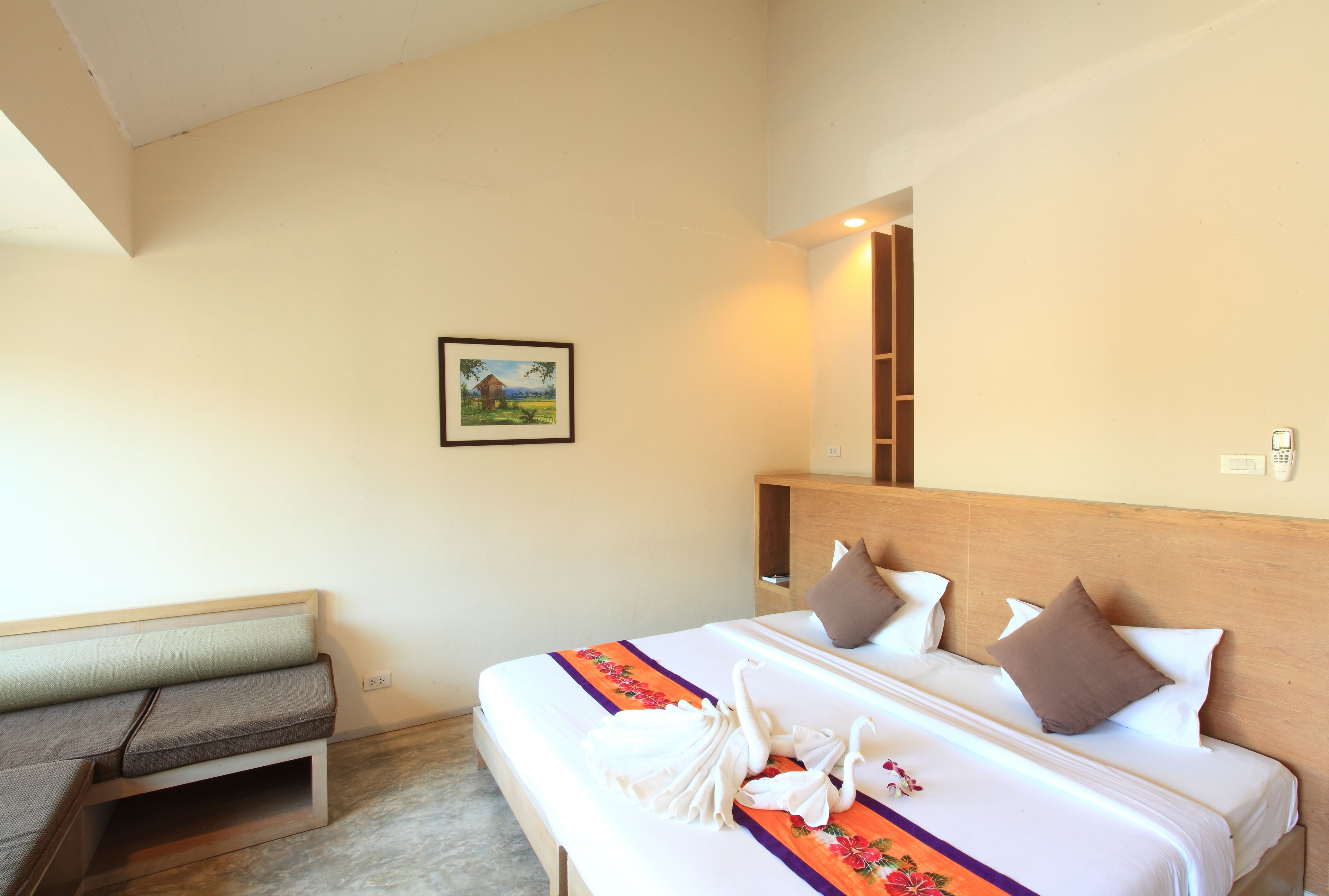 A hotel room with a bed, a bench, and a painting on the wall.