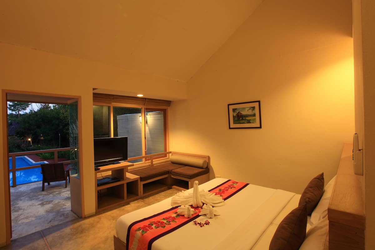 Ein Hotelzimmer mit Bett, Schreibtisch, Fernseher und Blick auf einen Swimmingpool.