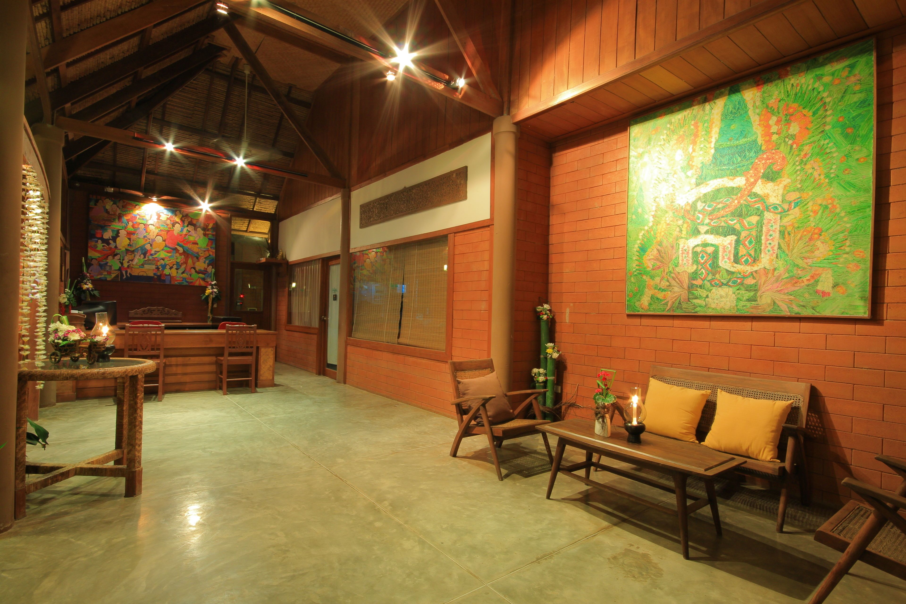 A spacious lobby with a high ceiling, wooden furniture, and a large abstract painting on the wall.