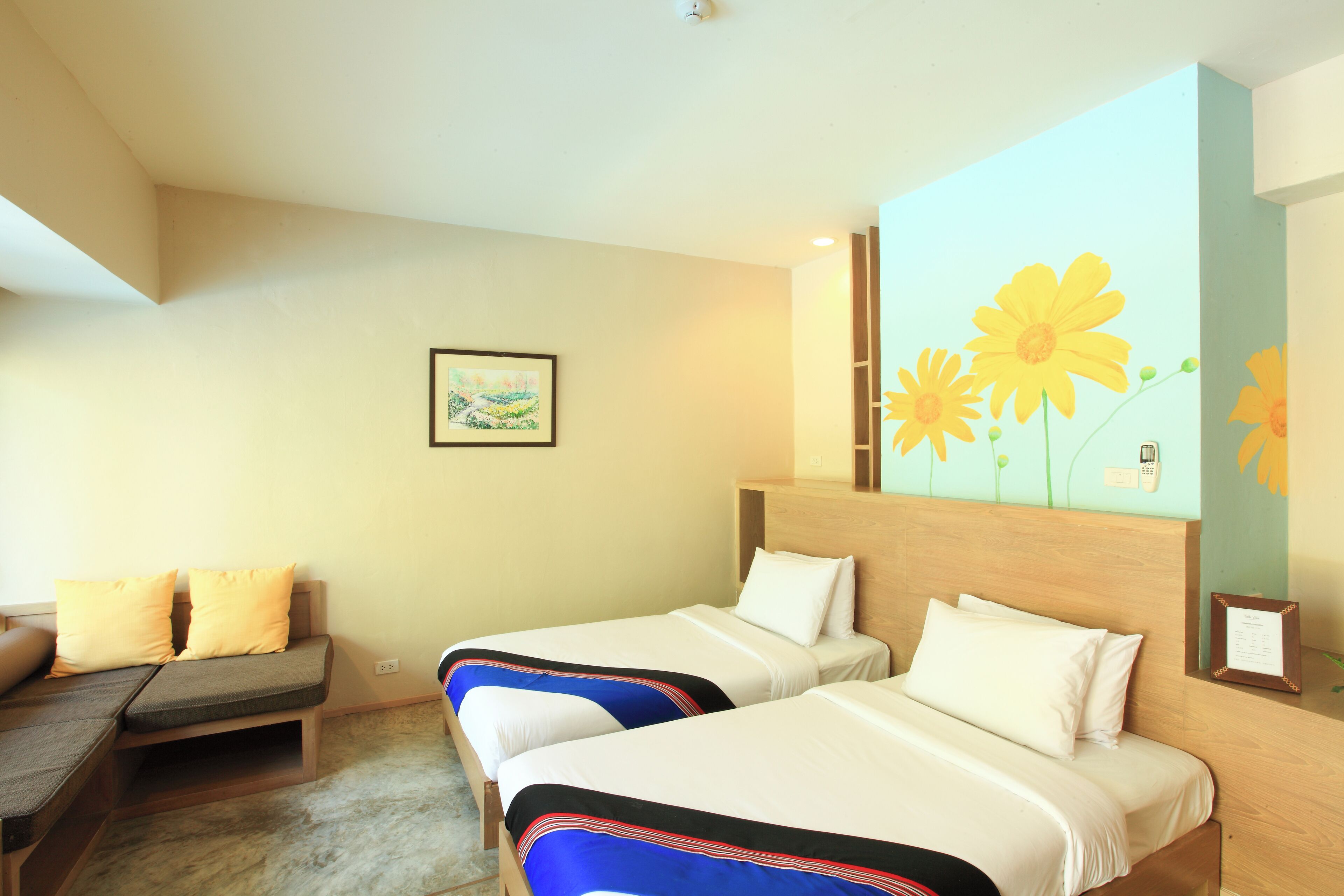 A hotel room with two beds, a sofa, a painting on the wall, and a floral mural.