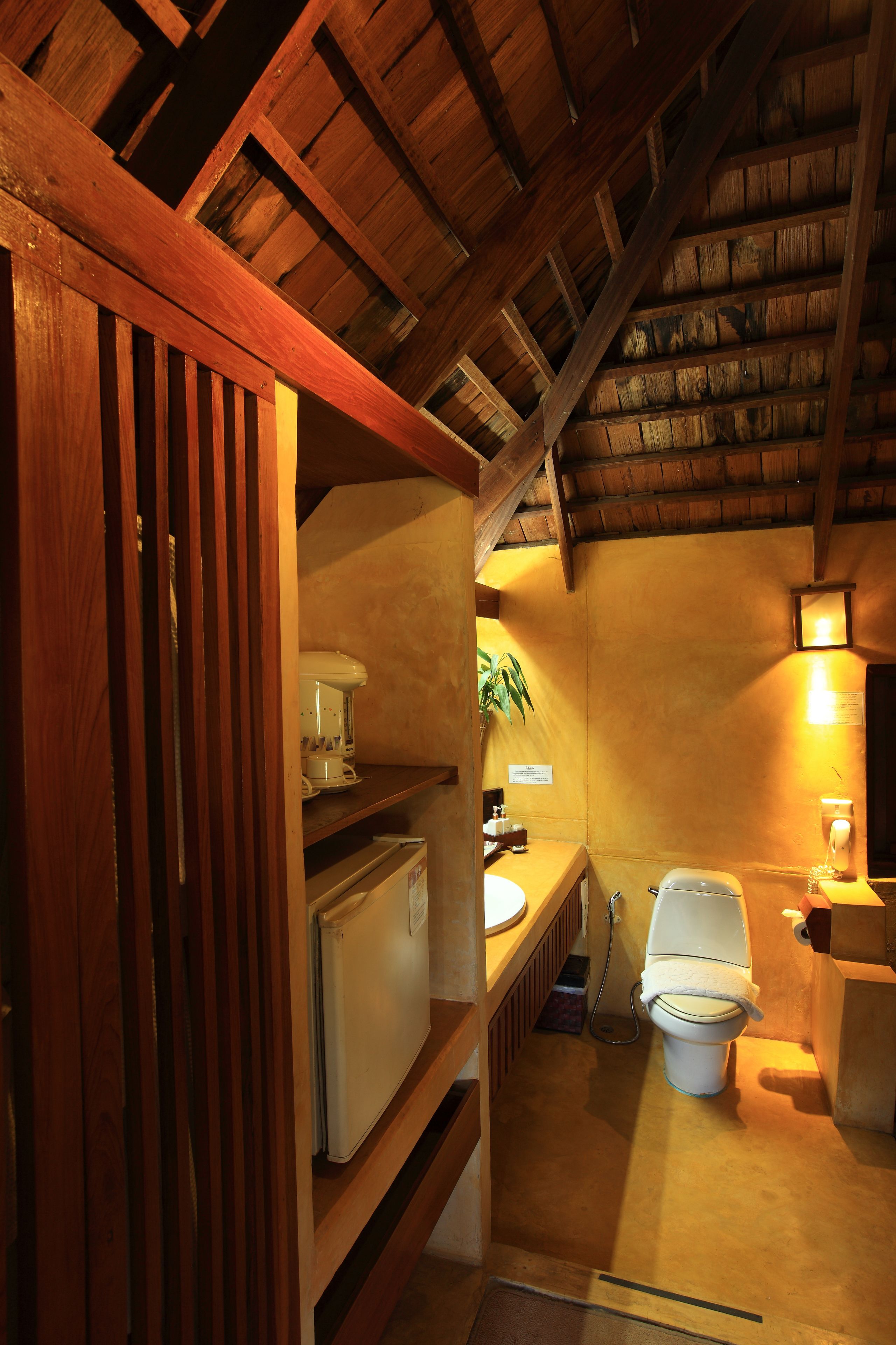 A compact kitchen with wooden beams, a refrigerator, a sink, and a stove.